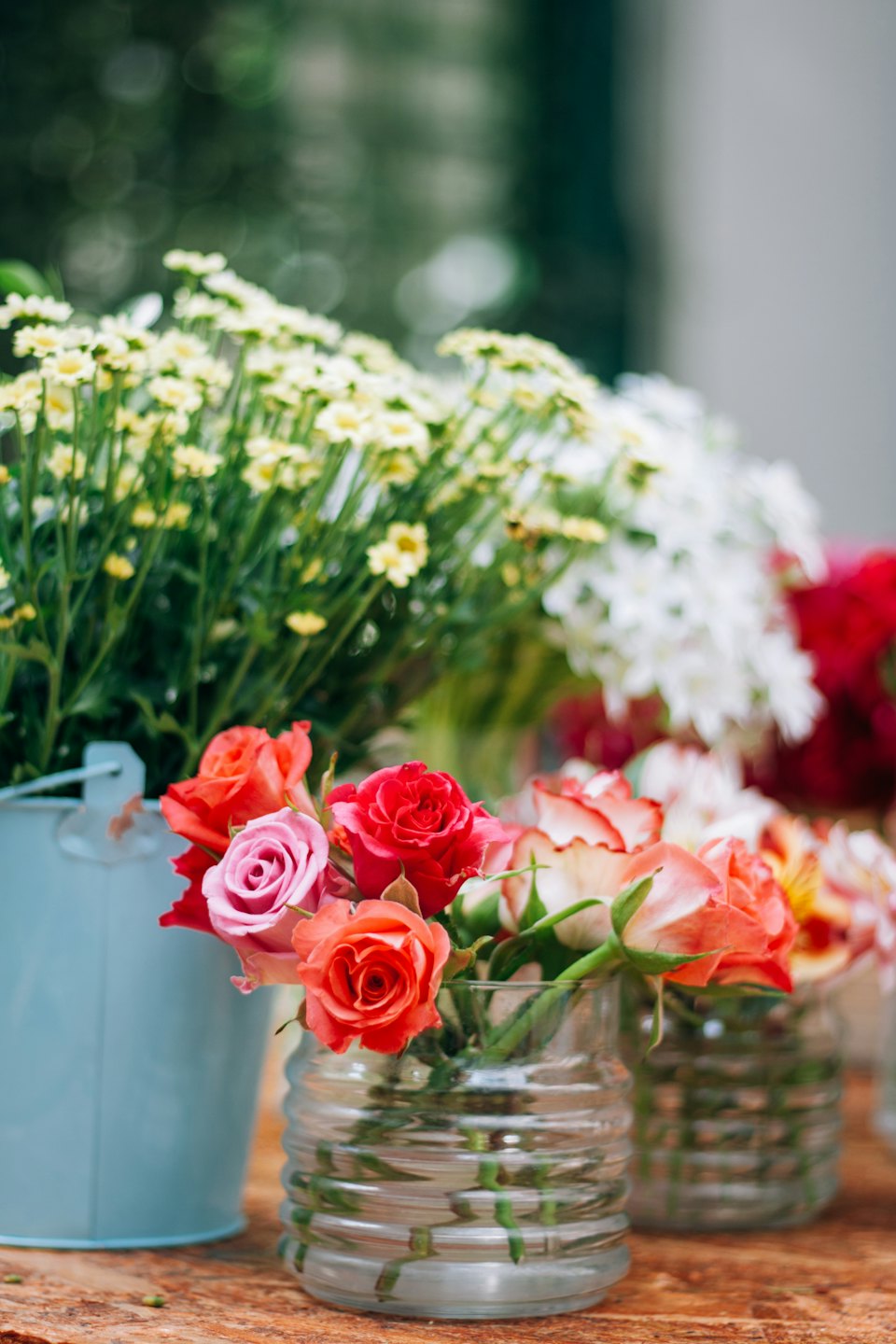 Frisch geschnittene Blumen in Vasen auf einem rustikalen Holztisch.