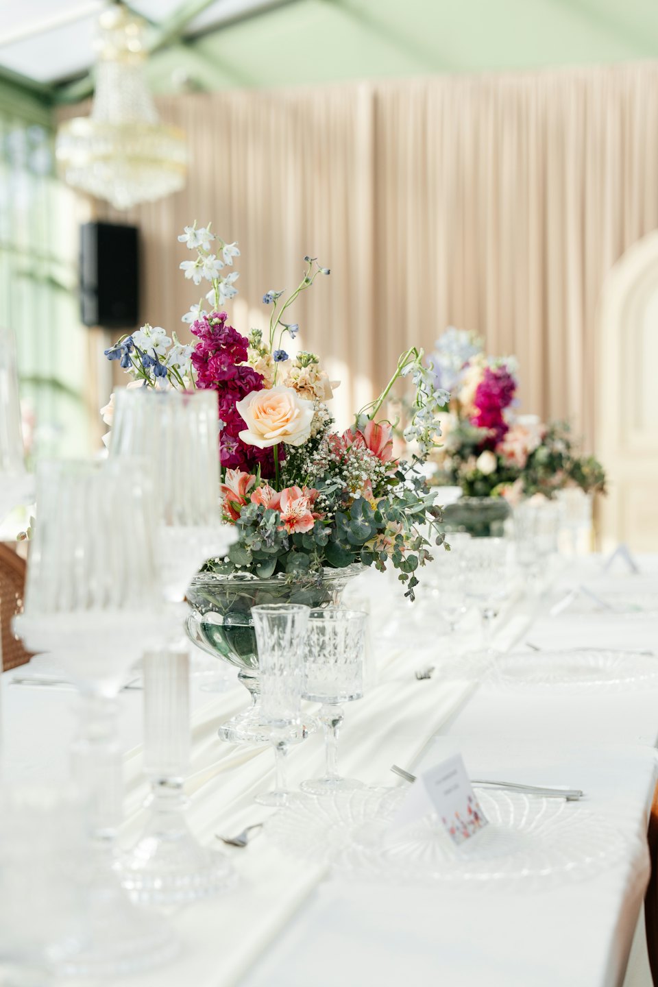 Elegante Tischdekoration mit einem lebendigen Blumenarrangement auf weißer Tischdecke.